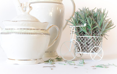 White miniature Bicycle decorated with green lavender branches on a white background. White forfor teapot and sugar bowl