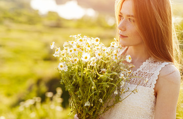 Young woman with bouquet of chamomiles