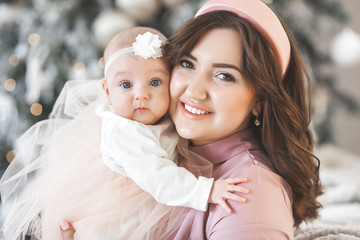 Obraz premium Young attractive mother carrying her little baby. Mom holding her cute child. Happy young family indoors.