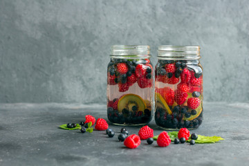 Fresh cool detox drink with raspberries, blueberries and kiwi in mason jar mug. Lemonade in a glass with a mint. The concept of proper nutrition and healthy eating. Fitness diet. Copy space for tex