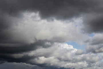 Dramatic storm grey cumulus clouds against blue sky background texture