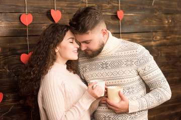Happy man and woman in sweaters drinking tea in valentine day