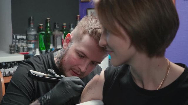 Video of man doing dark tattoo for woman in studio