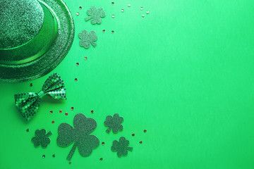 Happy Saint Patrick's Day greeting card with traditional symbols, shamrock, green attire. Green hat, bow tie, St Patricks Day shamrocks, golden confetti on green background, copy space