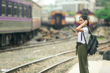 asian girl checking map on phone with backpack, travel by train, destination nature trip in summer.