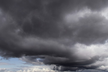 Dramatic storm grey cumulus clouds against blue sky background texture