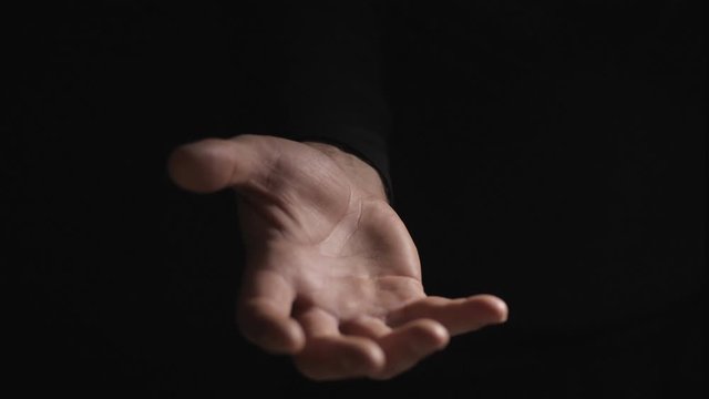 A hand on a black background invites you to enter. Climate lighting. Recorded in 4K 60fps. High-quality recording in a professional film studio.