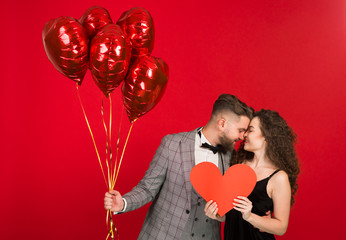 Joyful couple with heart shaped balloons isolated on red background