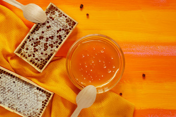 Concept of healthy ecological food with wooden tableware. Bee products with a large number of vitamins that increase the immune system. Honey, perga, honeycomb on a background of contrasting colour