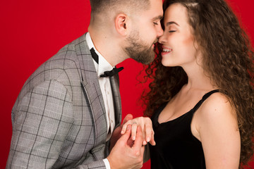 Man proposing to girlfriend and kissing her isolated on red background