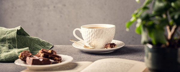 Coffee break composition with cup of coffee and chocolate. Healthy breakfast concept with copy space. Toned photo, banner