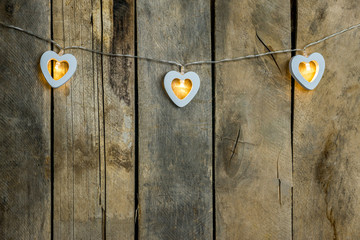 Old wooden background close-up with a garland of two white burning hearts. The concept of a Declaration of love, romantic relationships, Valentine's day in grunge style. Copy space