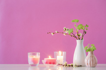spring cherry flowers and candles on pink background