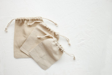 Canvas bags with drawstring, mockup of small eco sack made from natural cotton fabric cloth flat lay on white background. Flat lay, top view.