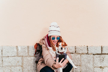 woman taking a self portrait with her cute dog outdoors. technology and pets concept
