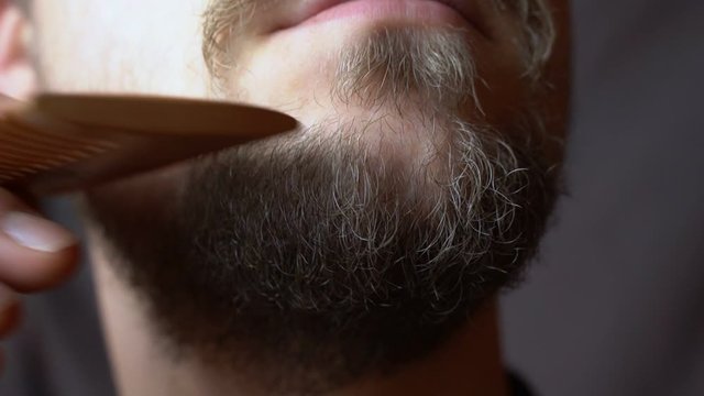 A man combing his beard with a comb