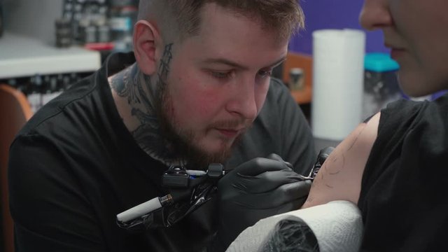 Footage of doing dark tattoo of snake for woman in studio