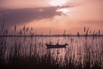 boat on the background of the sunset with rays breaking through the clouds on proud in Canet-en-Roussillon