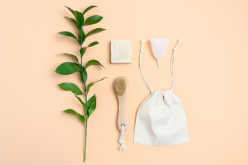 Layout of green leaves and zero waste accessories for personal hygiene on yellow pastel background.