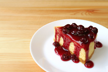 Plate of blueberry cheesecake served on wooden table with copy space