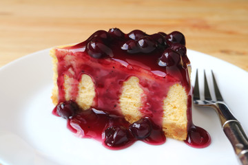Closeup a slice of cheesecake with blueberry sauce on white plate