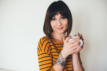 Woman with tattoo drink coffee on white background