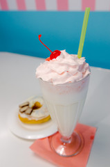 Closeup of fresh creamy vanilla milkshake with donut