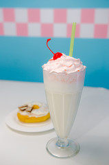 Glass of vanilla milkshake with donut