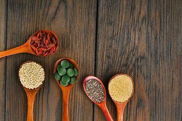 Goji berries, amaranth seeds, chia seeds, quinoa seeds, spirulina tablets in the spoons on a wooden...