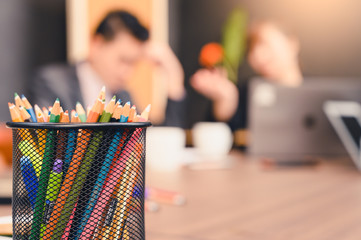 the abstract image of the pencils on the table and the meetings of business people is the backdrop. The concept of agreement, deal, business, cooperation, partnership and successful.