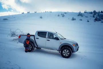 Fotobehang Pickup truck on road, Beautiful winter road under snow mountains. © YURII Seleznov