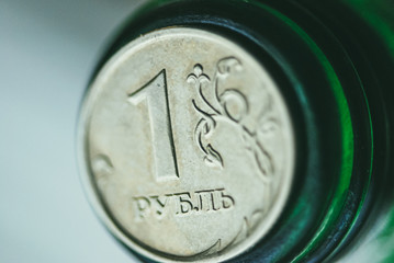 One Russian ruble lies on the neck of a green glass bottle. Selective focus macro shot with shallow...