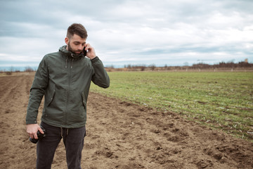 Young farmer working in a wheat field, talking mobile phone