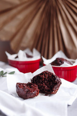 Chocolate muffins in red cups. Small glazed ceramic ramekin with brown cakes on a gray and white background.