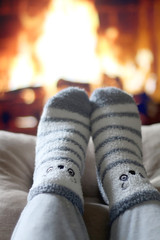 Feet in cute fuzzy socks in front of a fireplace. Selective focus.