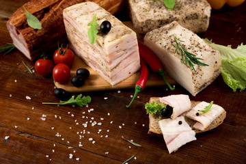 Composition of different smoked meat with spices and herbs on wooden background