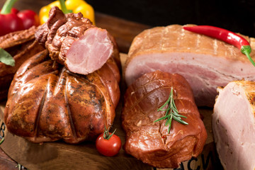 Composition of different smoked meat with spices and herbs on wooden background