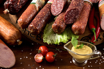 Different smoked sausages with vgetables and ingredients on wooden background