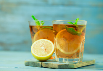 Iced tea with lemon slices and mint on wood background