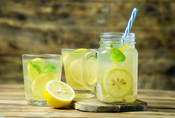 Lemonade or mojito cocktail with lemon and mint on wood background