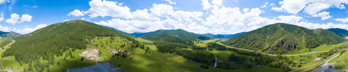 Fototapeta na wymiar Aerial panoramic banner view of landscape with mountains, green trees, field, road and river under blue sky and clouds in summer