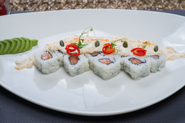 Traditional rolls with fish and rice on a white plate with sauce and wasabi. Japanese food.