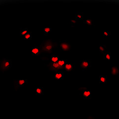 Fototapeta na wymiar Blurred red lights in the beautiful shape of the hearts on the black background.