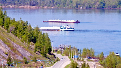 Steep car descent to the pier on the Volga. Along the coast are two bulk carriers with crushed...