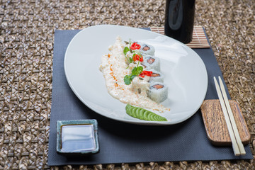 Traditional rolls with fish and rice on a white plate with sauce and wasabi. Japanese food.