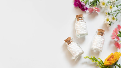 Homeopathic globules​ bottle with wildflowers​ on white backgound. Homeopathy alternative...