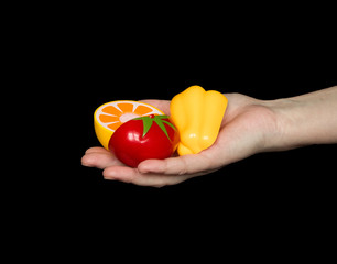 Plastic toy vegetables and fruits on hand on a black background. The concept of healthy eating, proper nutrition for children and adults.