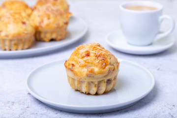 Muffins with ham and cheese. Homemade baking. In the background is a plate with muffins and a cup of coffee. Close-up.