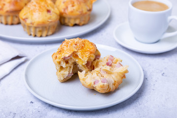 Muffins with ham and cheese. Homemade baking. In the background is a plate with muffins and a cup of coffee. Close-up.