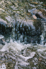 Flowing water and wet rocks in summer park